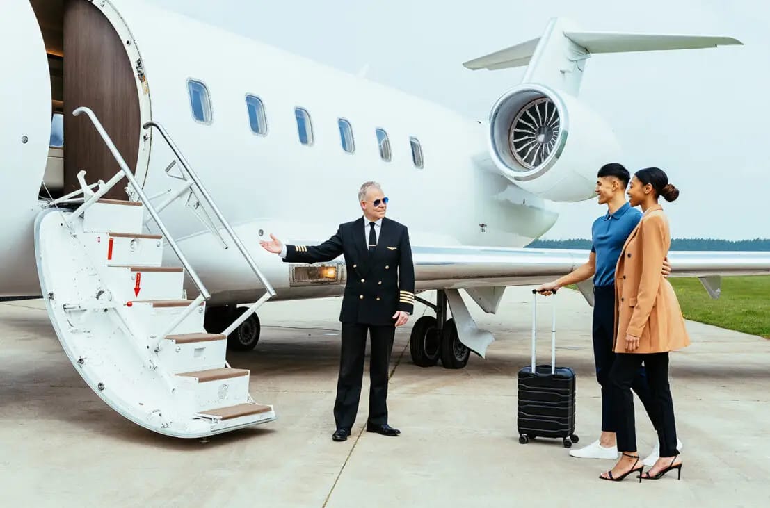 Pilot welcoming two passengers beside a private jet